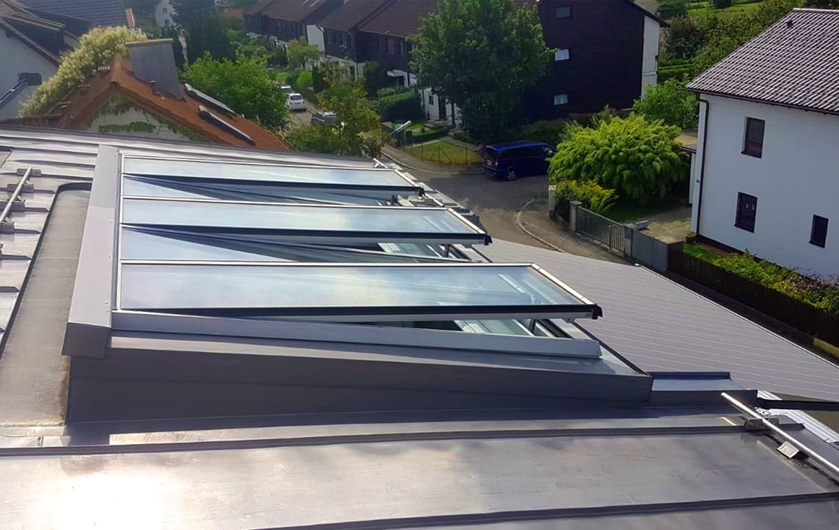 Drei geöffnete Fenster einer Pultdach-Verglasung auf einem Metalldach Drei geöffnete Fenster einer Pultdach-Verglasung auf einem Metalldach