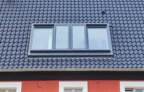 Außenansicht (Nahaufnahme) eines Dachschiebefensters über außenliegende Schienen.