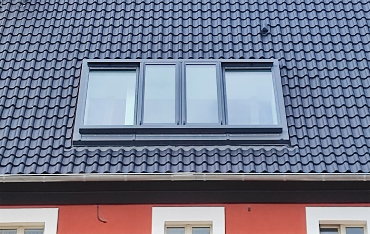Außenansicht (Nahaufnahme) eines Dachschiebefensters über außenliegende Schienen.