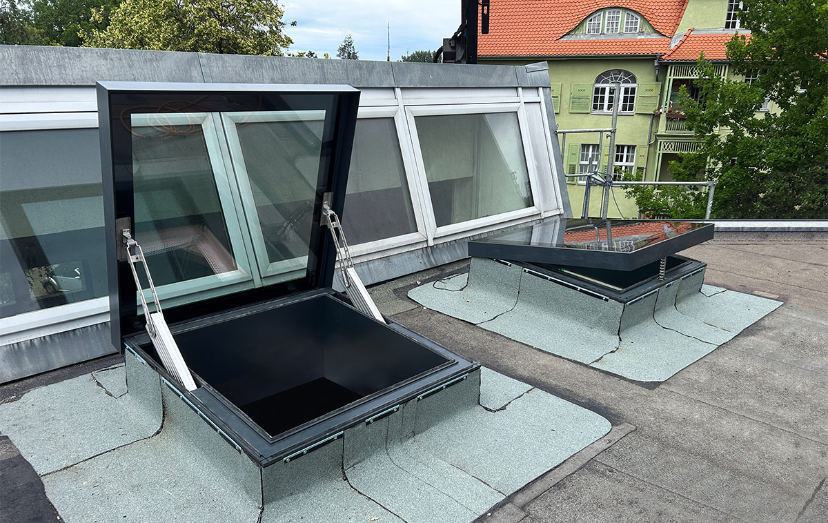 GLASOLUX SkyVision ACCESS Ausstiegsfenster und daneben ein leicht geöffnetes COMFORT auf dem Flachdach der St. Ursula Schule in Berlin.
